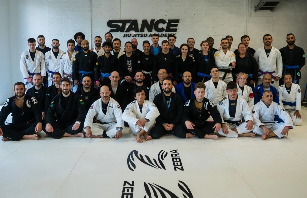 A full kids class sitting on the mat with parents and coaches behind them