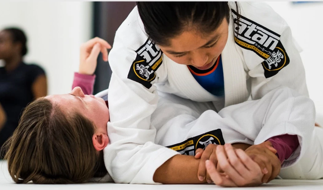 Women in gis sitting together on the mat during a women-only class